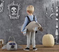 a young boy standing in front of a chalkboard wall with halloween decorations on it