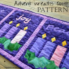 a quilted table runner with the words joy written on it and candles in purple