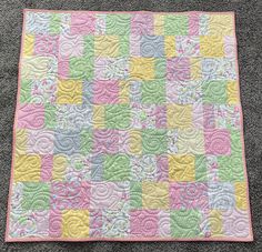 a colorful quilt is laying on the floor in front of a gray carpeted area