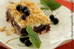 a piece of cake sitting on top of a white plate with blueberries and green leaves