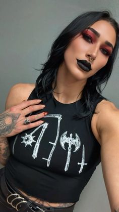 a woman with black lipstick and piercings on her face, wearing a shirt that says punk