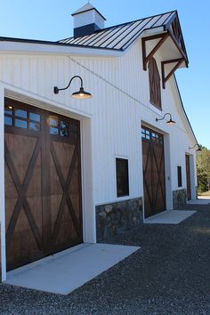 two brown doors are on the side of a white building with stone and wood accents