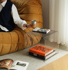 a person sitting on a couch with a book and coffee cup in front of them