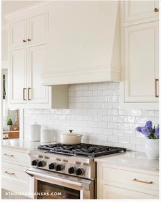 a stove top oven sitting inside of a kitchen next to white cupboards and drawers