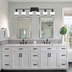 a bathroom with two sinks, mirrors and lights on the wall above them is shown