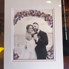 a couple posing for a wedding photo in front of a floral arch with the bride and groom