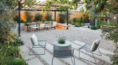 an outdoor dining area with chairs, tables and plants on the ground in front of it