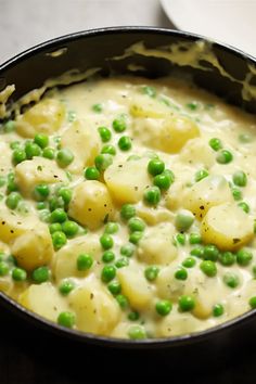 a pan filled with potatoes and peas on top of a table