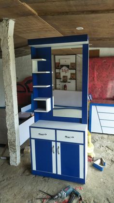 a blue and white cabinet sitting in the middle of a room with tools on the floor