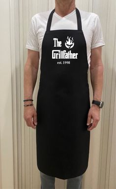 a man wearing an apron with the grillfather logo on it, standing in front of a door