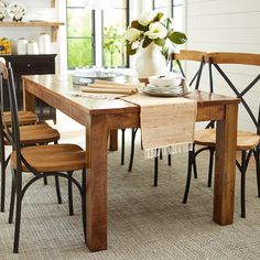 a dining room table with chairs and a vase on it