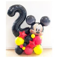 a mickey mouse balloon in the shape of a number with stars and balloons attached to it