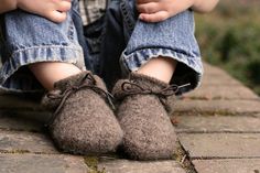 a child's feet wearing slippers and sitting on a stone surface with their hands behind them