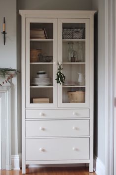 a white china cabinet with glass doors and drawers