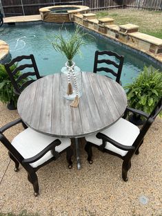 a wooden table with four chairs around it near a swimming pool in the back yard