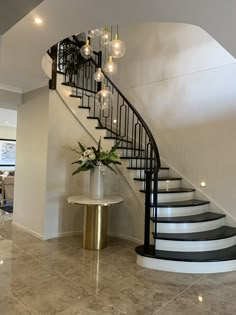 a spiral staircase in a modern home with marble floors and gold accents on the railing