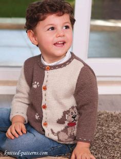 a little boy sitting on the floor wearing a brown and white sweater with bear designs