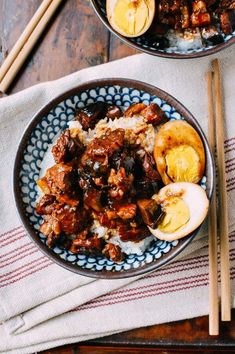 two bowls filled with food and chopsticks on top of a wooden table next to each other