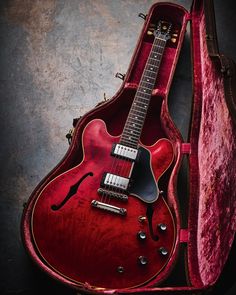 an electric guitar in a red case on a black background with a pink velvet lining