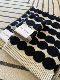 two pieces of black and white patterned fabric with tags on them sitting on a bed