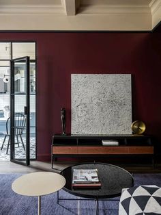 a living room with red walls and black furniture in the center, along with a large painting on the wall