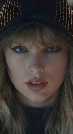 a close up of a person wearing a hat with long hair and makeup on her face