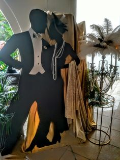 a mannequin dressed in a tuxedo and bow tie standing next to a palm tree