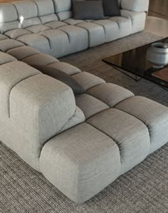 a large gray couch sitting on top of a carpeted floor next to a coffee table