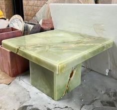 a green table sitting on top of a cement floor next to other boxes and containers