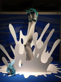 a woman's legs and shoes on display in front of a blue wall with white paint