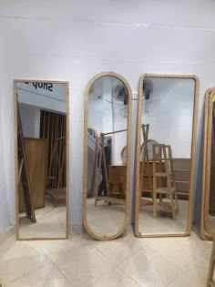 three mirrors sitting next to each other on top of a tiled floor in front of a white wall