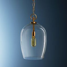 a clear glass light fixture hanging from a gold chain on a blue background with an empty bulb in the center