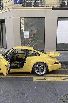 a yellow sports car parked on the side of the road in front of a building