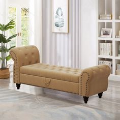 a tan bench sitting on top of a hard wood floor next to a book shelf