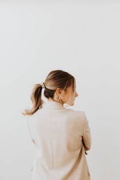 a woman in a white blazer and black pants is looking off to the side