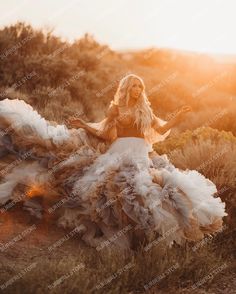 a woman in a long dress is walking through the grass