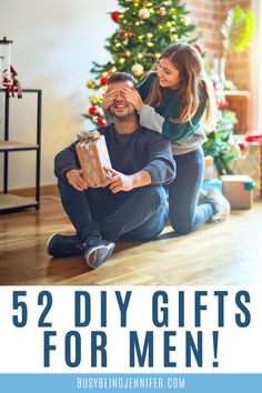 a man kneeling on the floor holding a wrapped present while his girlfriend gives him a gift