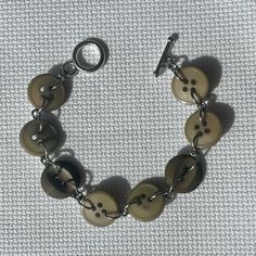 a close up of a bracelet with buttons on it and a metal chain attached to the clasp