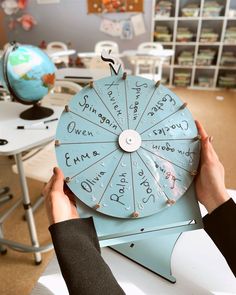 a person holding up a spinning wheel with writing on it in front of a desk