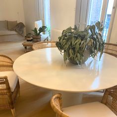 a white table with chairs and a potted plant on it in a living room