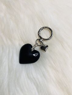 a black heart shaped keychain sitting on top of a white fur