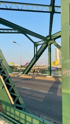 a green metal bridge with graffiti on it