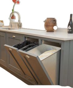 an open dishwasher sitting on top of a kitchen counter next to a sink