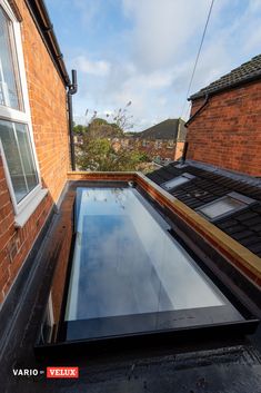 a flat roof with a skylight on the top and side of it, in front of a brick building