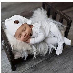 a baby sleeping on top of a wooden bed next to a white sheep headdress