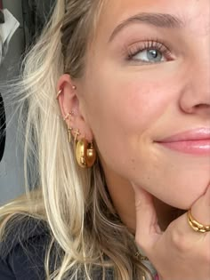 a close up of a person wearing earring and looking at the camera with a smile on her face