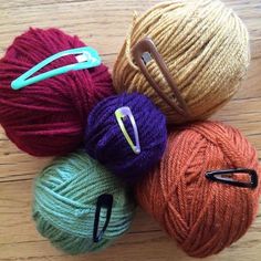 several balls of yarn sitting on top of a wooden floor next to scissors and knitting needles