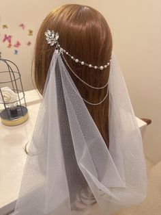 the back of a woman's head wearing a veil with pearls and beads on it