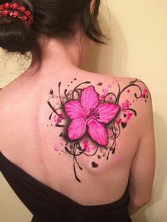 a woman's back with pink flowers painted on her shoulder and black ink splats