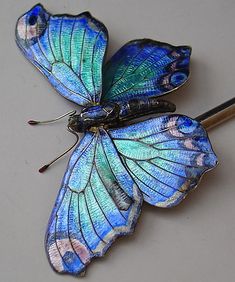 a blue butterfly brooch sitting on top of a white surface